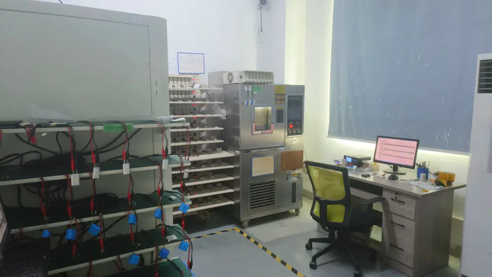 Battery testing room with cycling racks, test equipment, and monitored workstations supporting controlled performance evaluation.